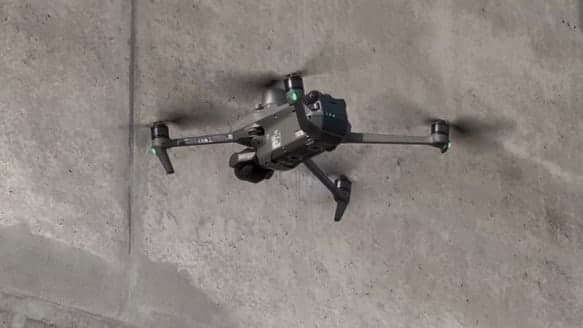 Eine Drohne im Schwebeflug dicht vor einer Betonwand, wie bei der Inspektion eines Bauwerks