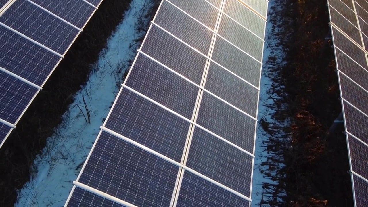 Reihen von Photovoltaikmodulen aus der Luft, im Gegenlicht der tiefstehenden Sonne
