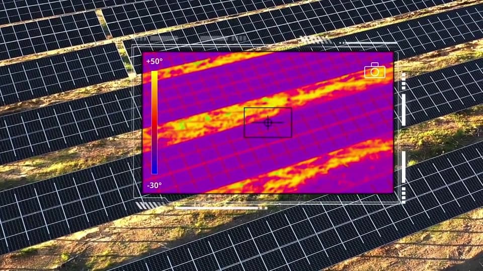 Reihen von Photovoltaikmodulen aus der Luft, darüber ein eingeblendetes Wärmebild mit Temperaturskala